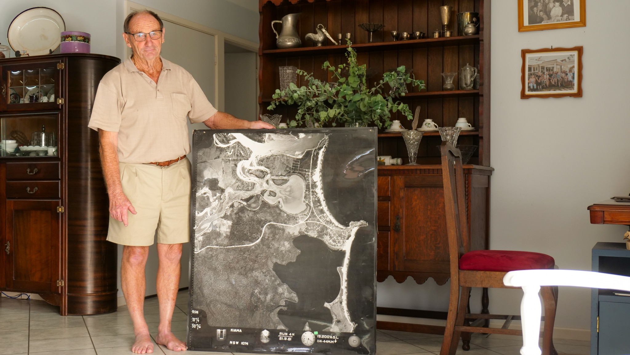 A man stands with a large aerial photograph of Orient Point taken 60 years ago.