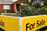 A house with a black and yellow for sale sign in front of it.