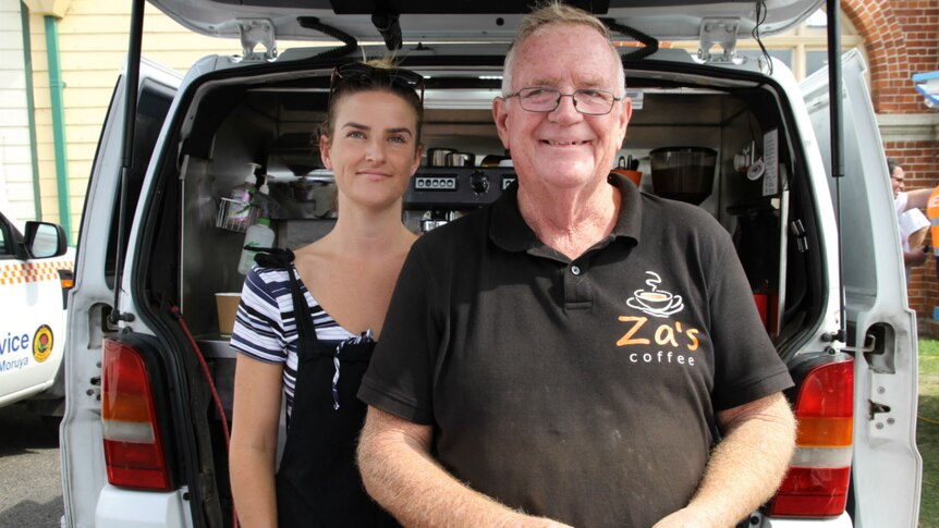 A man and young woman stand in front of a van