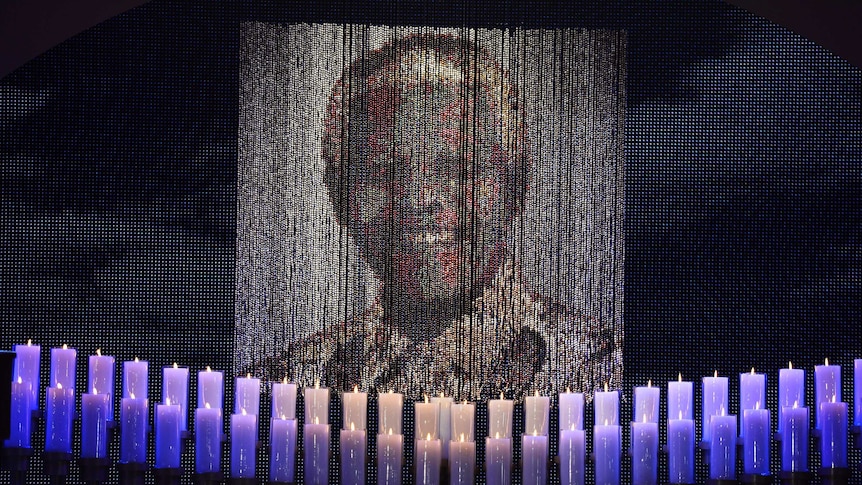 Candles lit under a portrait of Nelson Mandela