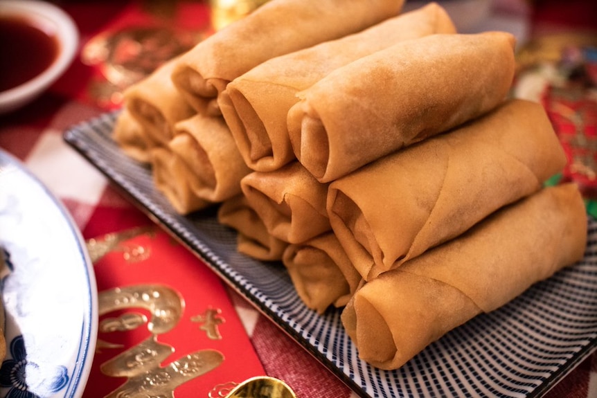 Lunar New Year spring rolls on a platter on a festive table setting.