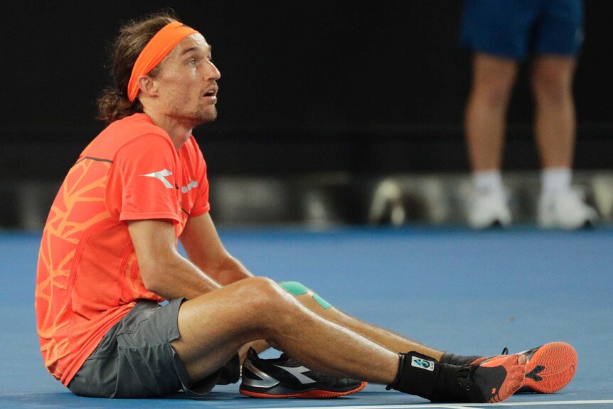 Alexandr Dolgopolov sits on the court with one shoe off during his Australian Open match against Matt Ebden.
