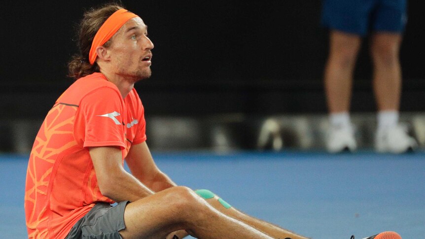 Alexandr Dolgopolov sits on the court with one shoe off during his Australian Open match against Matt Ebden.