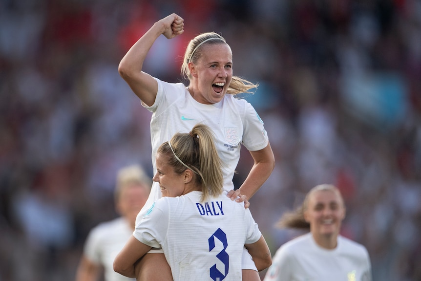 A soccer player wearing white jumps in the air in celebration