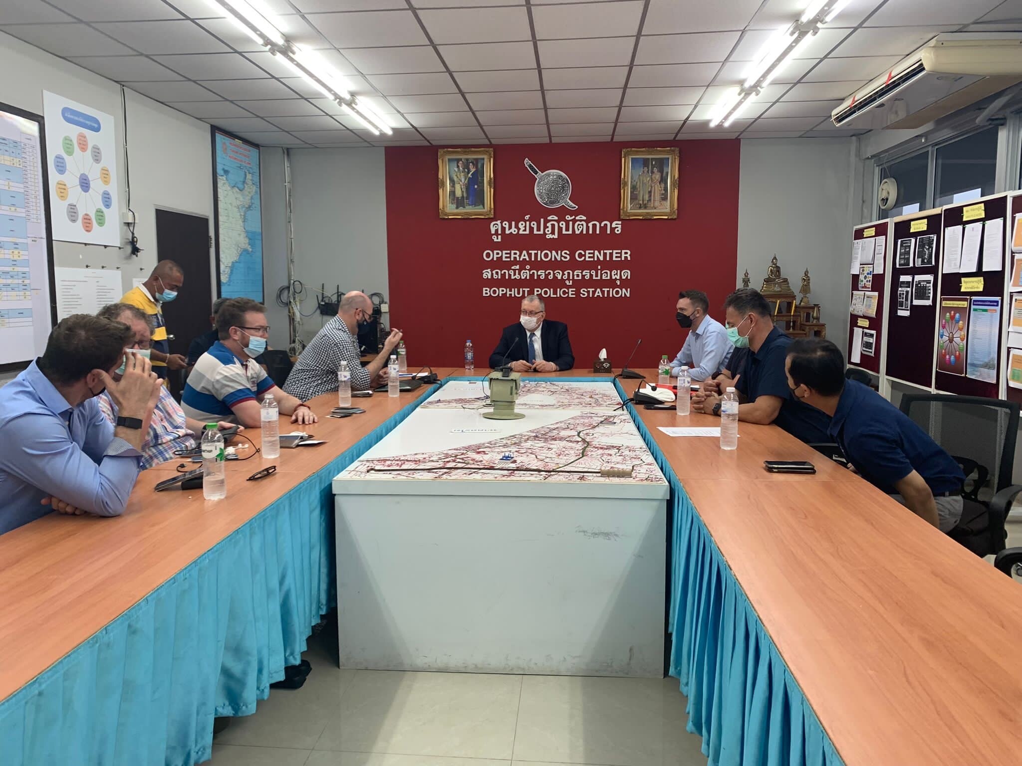 Australia's ambassador sets at the head of a U-shaped conference table speaking to several other men. 