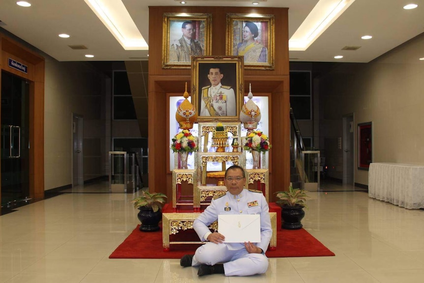 Sitting in front of photos of the Royal family, Narongsak Osottanakorn holds his letter from Thailand's King.