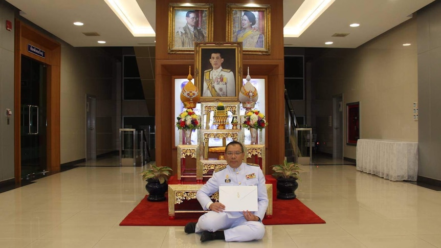 Sitting in front of photos of the Royal family, Narongsak Osottanakorn holds his letter from Thailand's King.