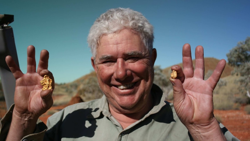 A photo of prospector Bill O'Connor holding two gold nuggets