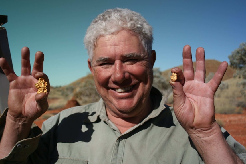 A photo of prospector Bill O'Connor holding two gold nuggets