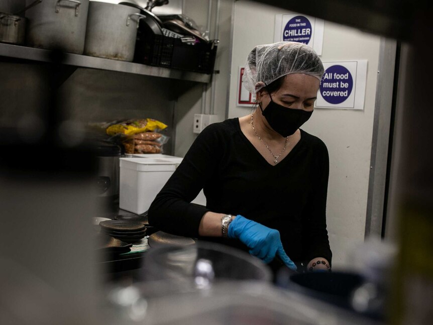 A woman wearing a face mask can be seen in a kitchen