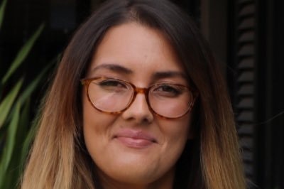 A woman with brown and blonde hair with glasses smiles