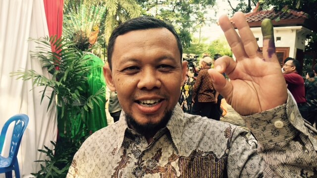 An Indonesian man shows off his ink-stained finger after voting in elections for Jakarta's next Governor
