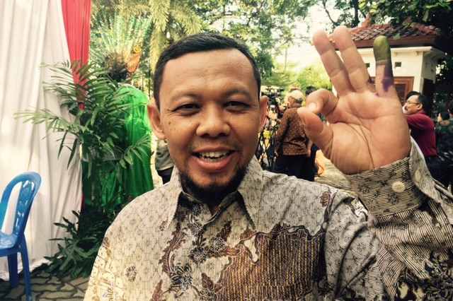 An Indonesian man shows off his ink-stained finger after voting in elections for Jakarta's next Governor