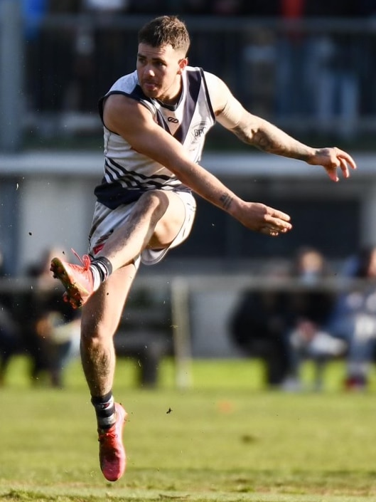 AFL player in the action of kicking a ball during a match