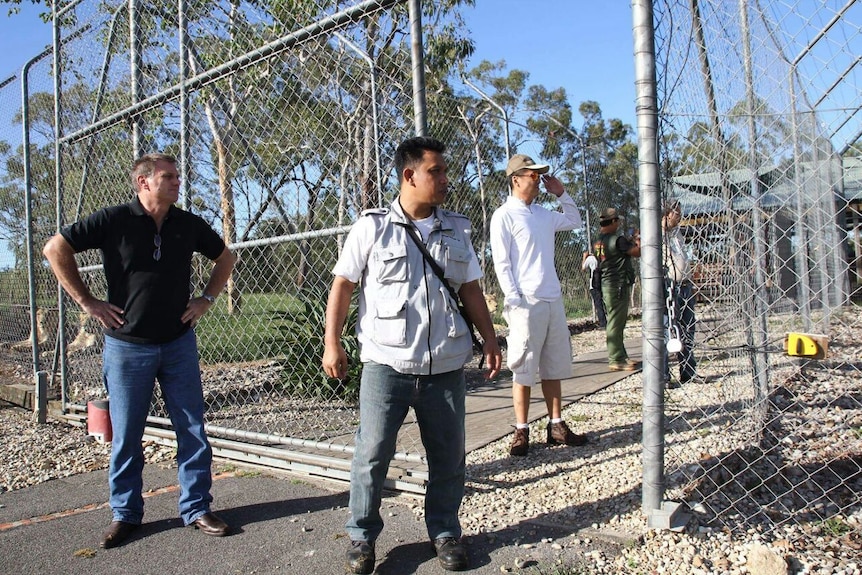 A photo of Tim Husband and a few other men standing outside some zoo gates.