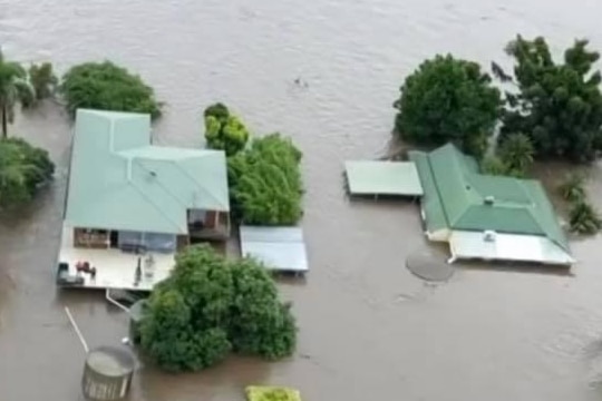 Arial picture of house with brown water up to its green roof. 