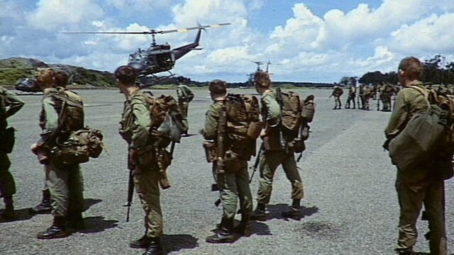 Group of soldiers on tarmac with helicopter