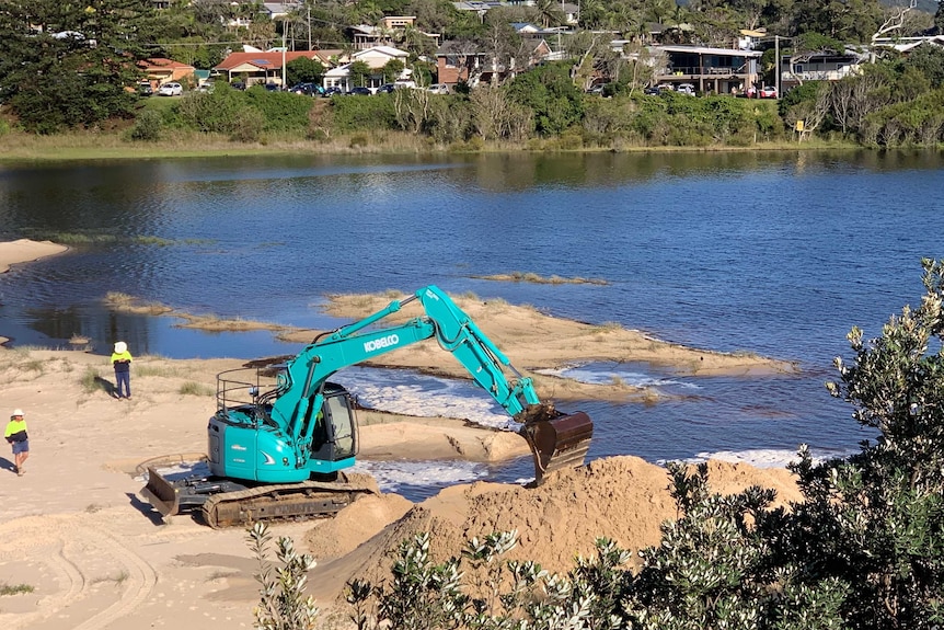 Excavator working to form a channel to open Lake Cathie south of Port Macquarie to the ocean.