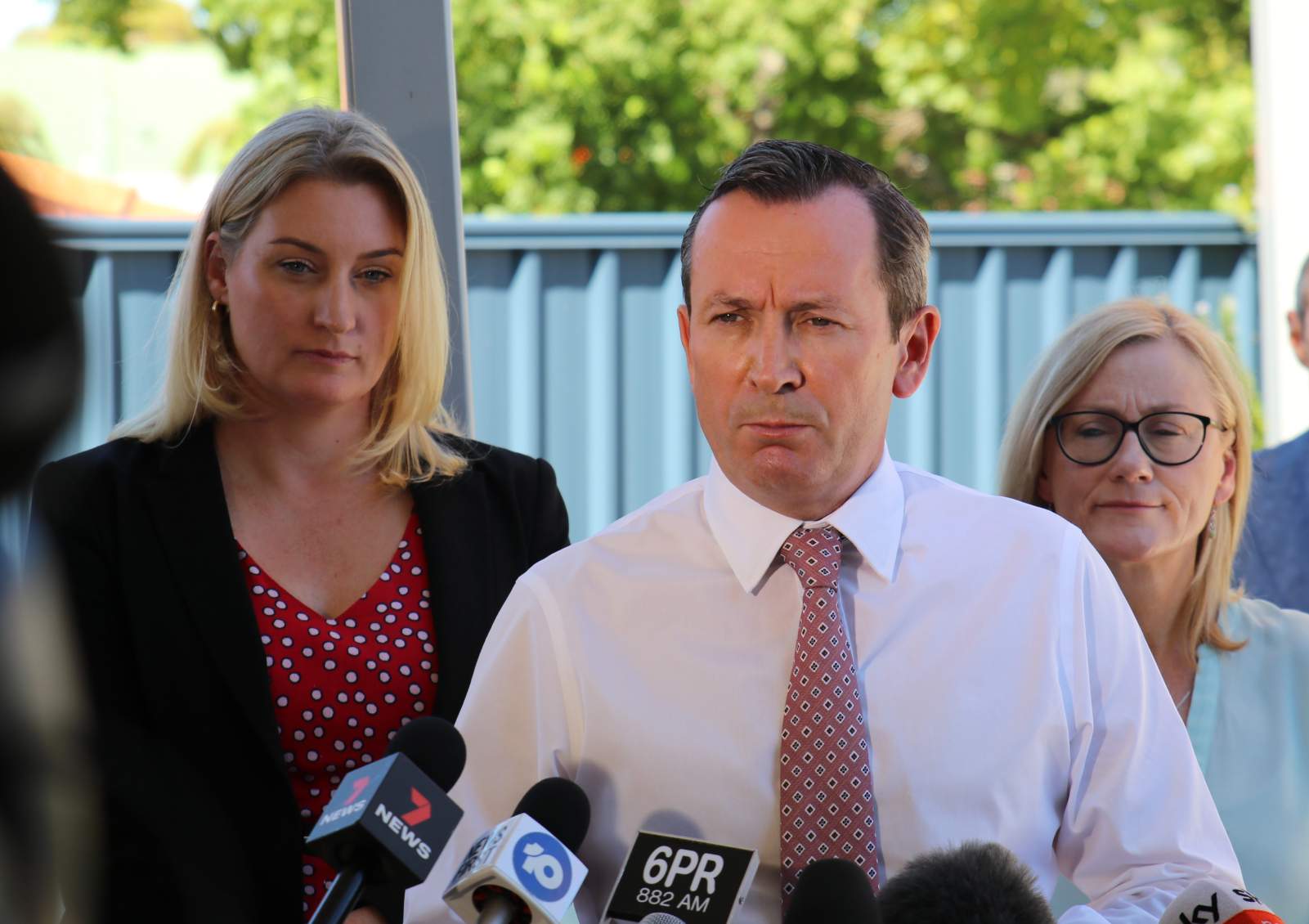 Two women stand behind Mark McGowan at a press conference