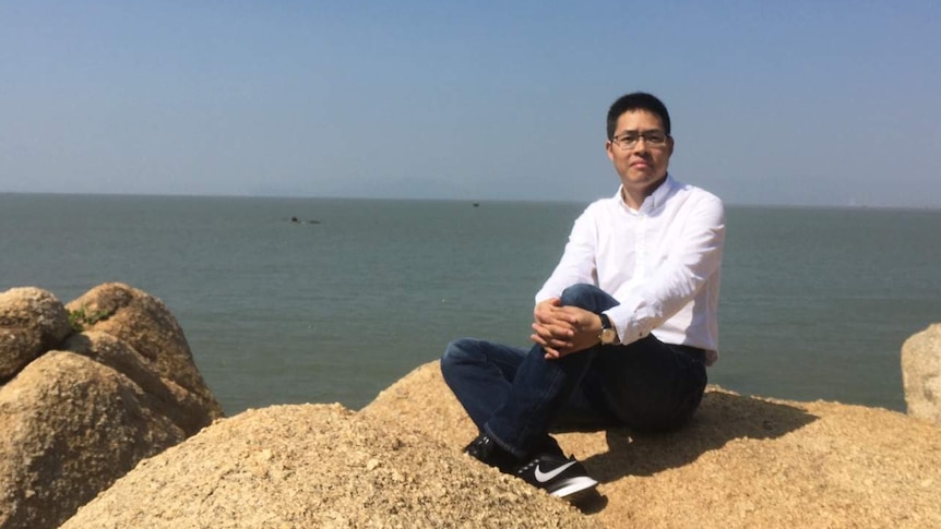 Chinese dissident Aizhong Wang sitting on the beach