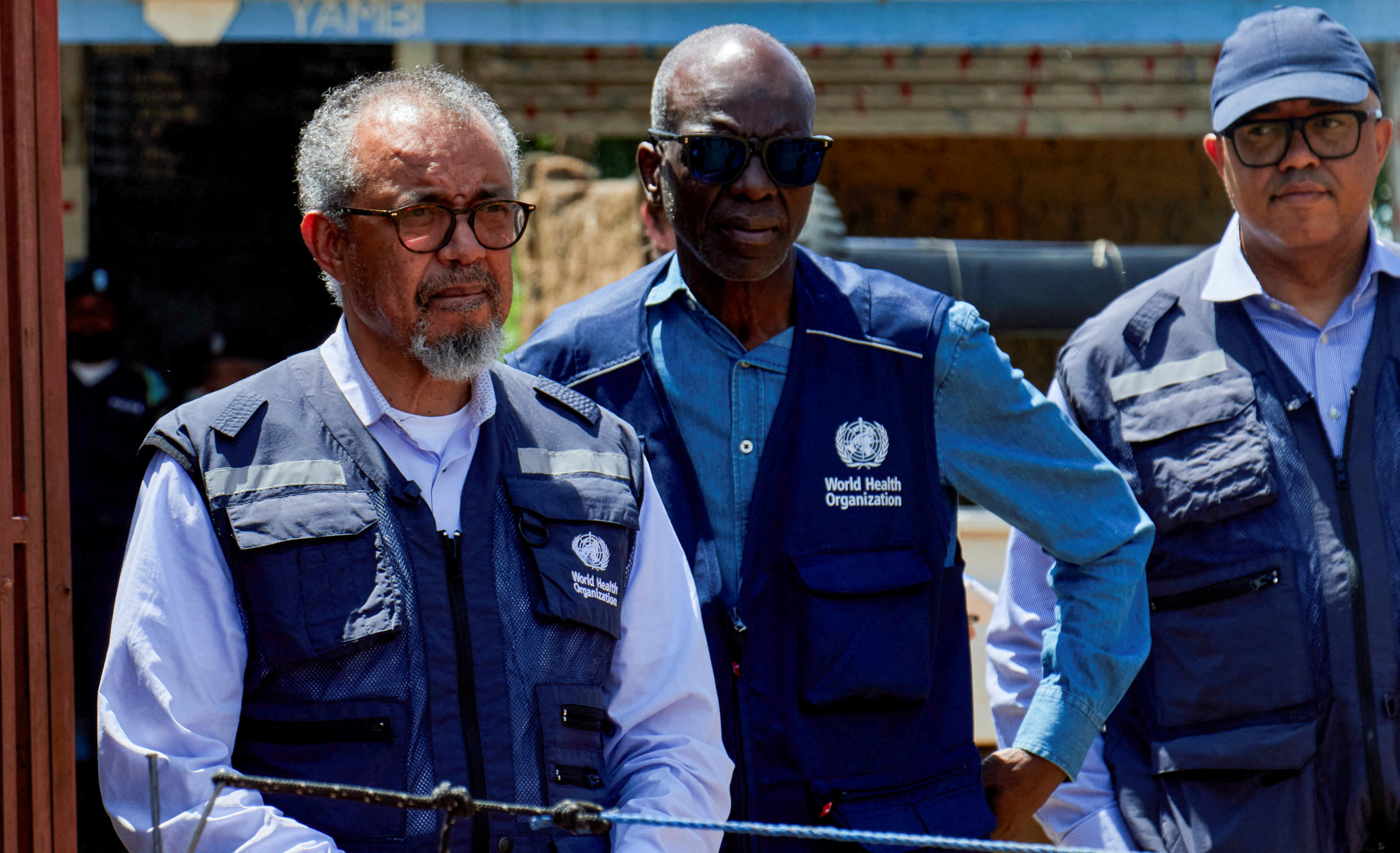 Trois hommes debout portant des gilets bleu marine et des chemises bleues