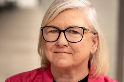 a woman in a pink jacket and black rimmed glasses
