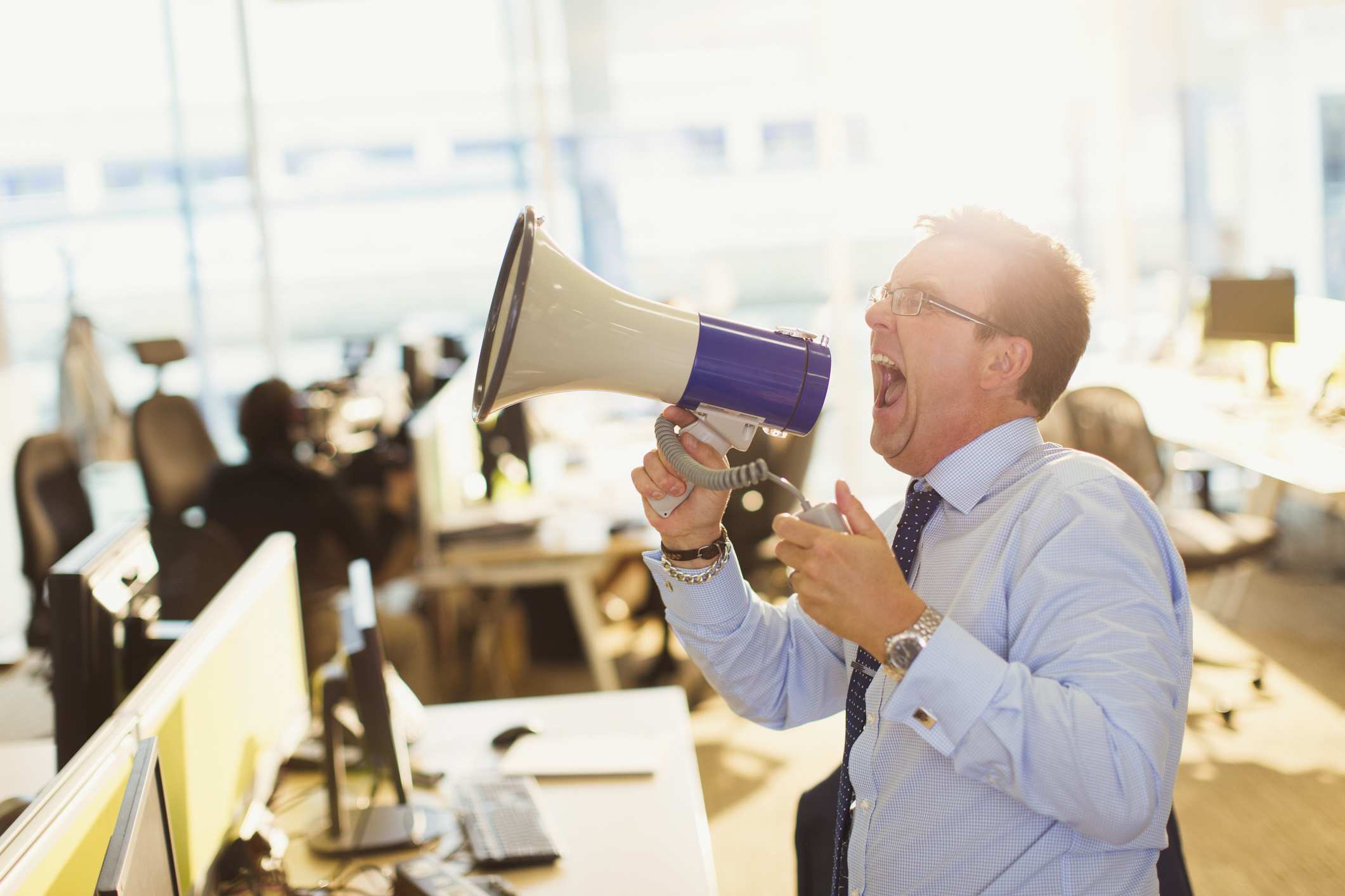Man on a megaphone in an open-plan office.