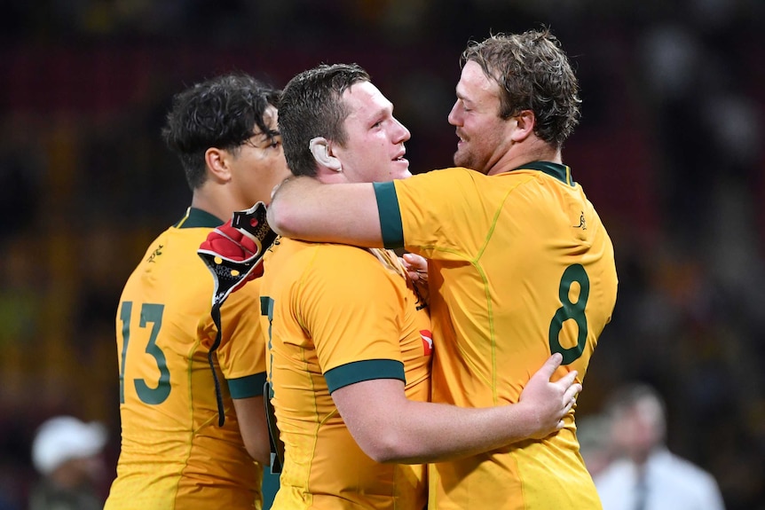 Two Wallabies players hug as they celebrate beating the All Blacks in Brisbane.