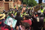 A group of anti-racism protestors face off against a line of mounted police.