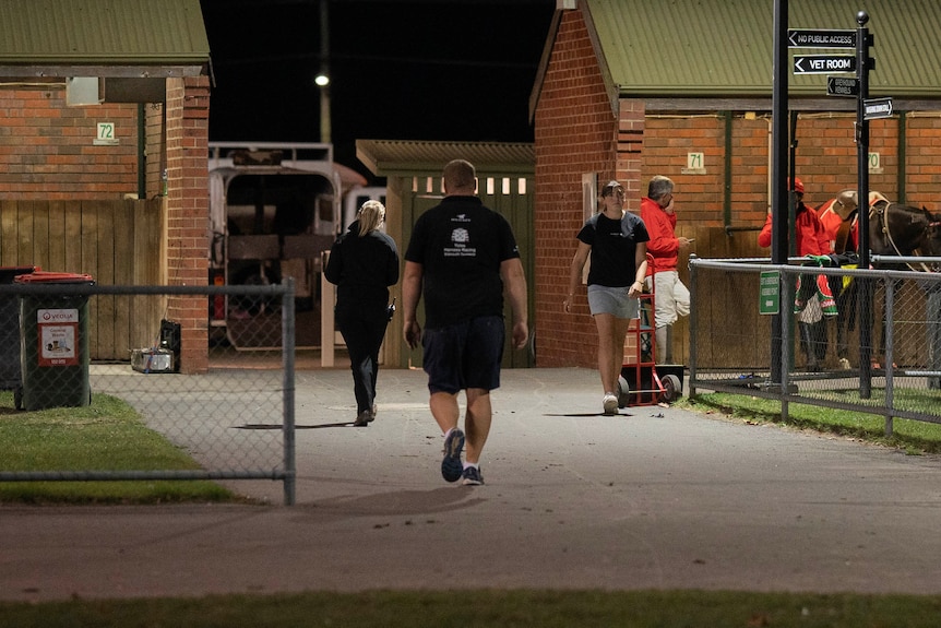 A man walks towards stables.