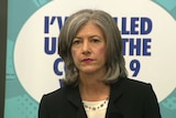 A woman with grey hair in front of a banner