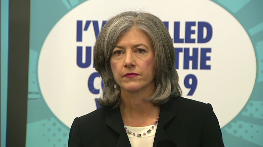 A woman with grey hair in front of a banner