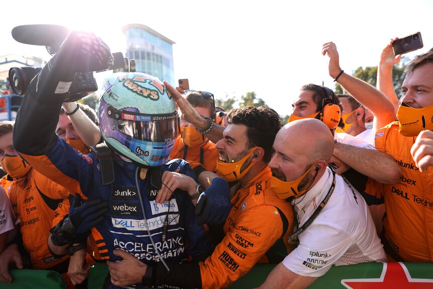 Race driver celebrates with his team after a victory.