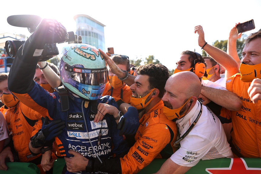 Race driver celebrates with his team after a victory.