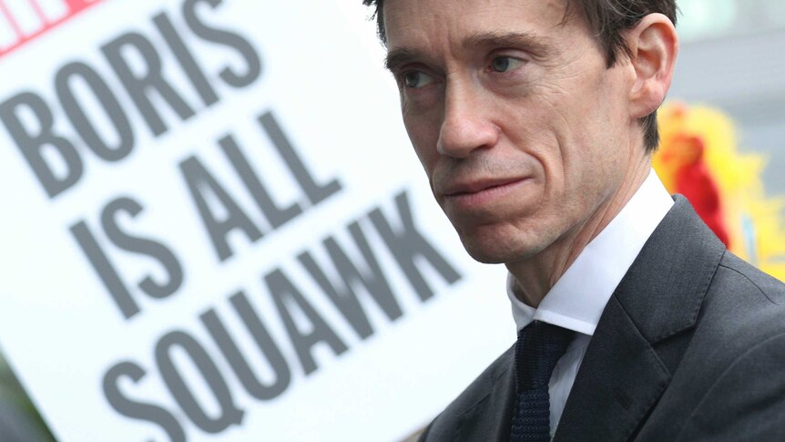 A close up of Rory Stewart with a sign in the background reading 'Boris is all squawk'.