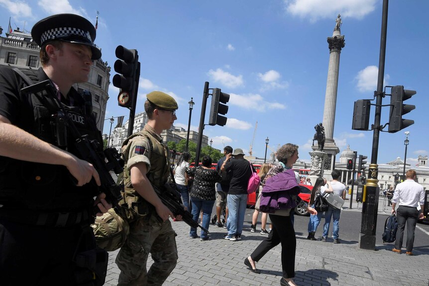 A soldier and a police officer walk past Trafalgar Square during a mobile patrol in central London.
