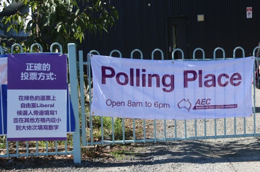 Two posters attached to a fence, one in English, the other Chinese. The English one says "POLLING PLACE".