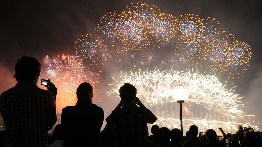 New Year's Eve revellers photograph the midnight fireworks off the Sydney Opera House