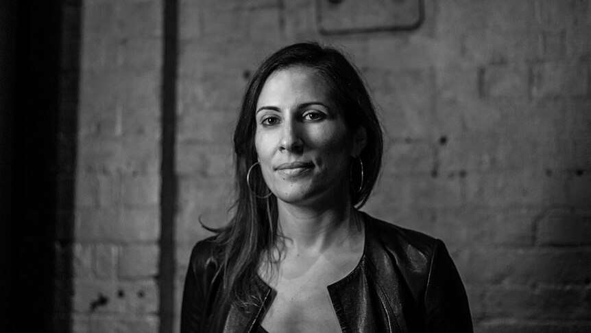 Black and white photo of director Adena Jacobs standing in front of concrete wall.