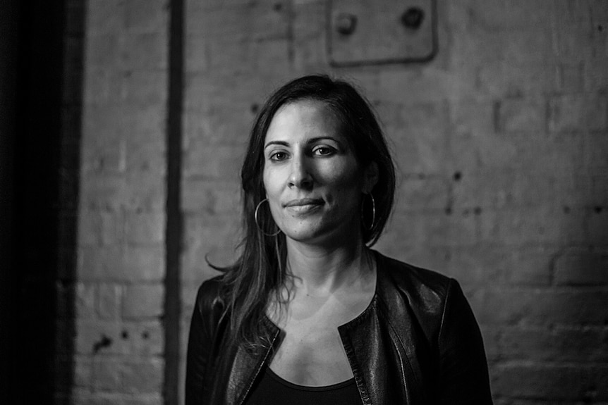 Black and white photo of director Adena Jacobs standing in front of concrete wall.