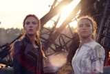 Scarlett Johansson and Florence Pugh stand in front of a pile of rubble, with determined expressions