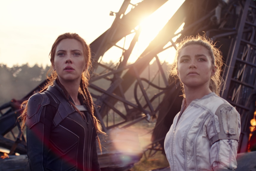 Scarlett Johansson and Florence Pugh stand in front of a pile of rubble, with determined expressions