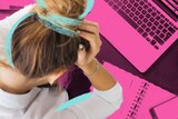 Stressed out woman leans over her computer at work