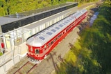 This is an aerial shot of a red and silver solar-powered train stopped at a station near Byron Bay.