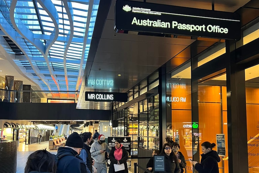 Queue of people in front of closed storefront inside larger mall