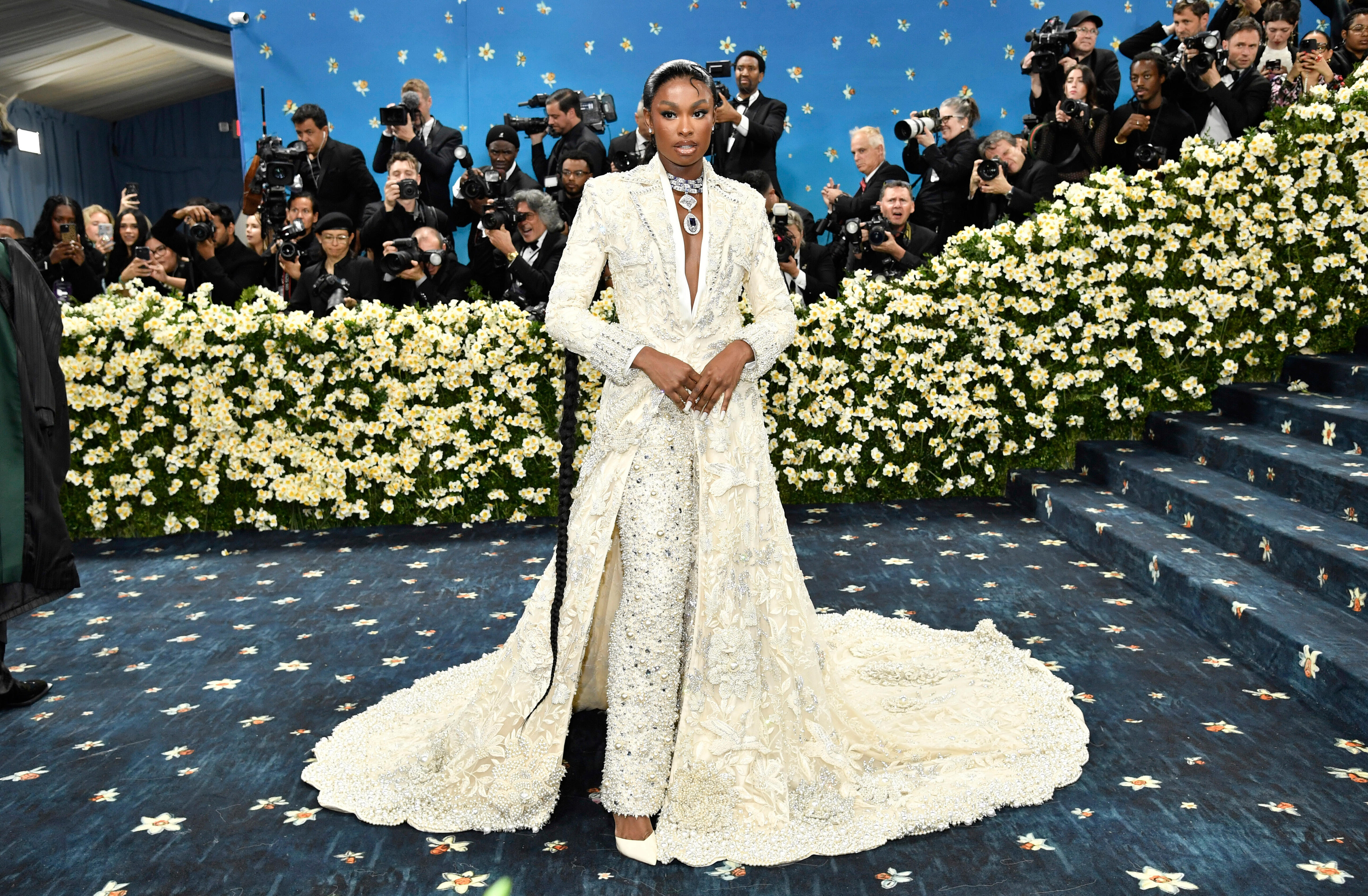 Coco Jones wearing white bedazzled pants with a matching tuxedo jacket with a long train