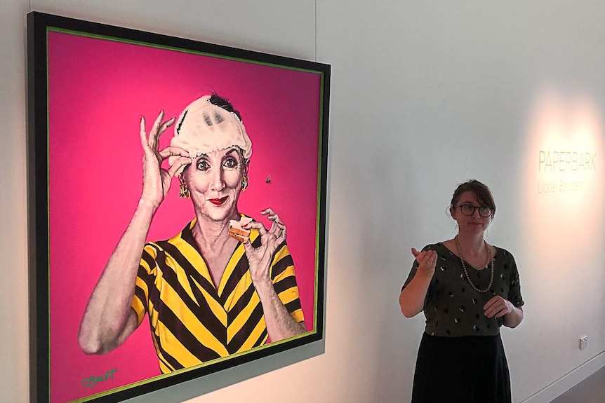 A woman uses sign language in an art gallery