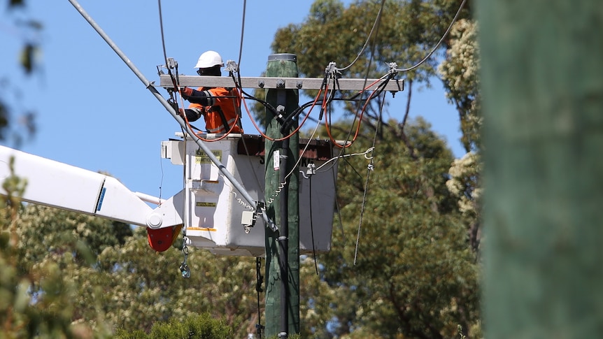 A person in a cherry picker works on power lines