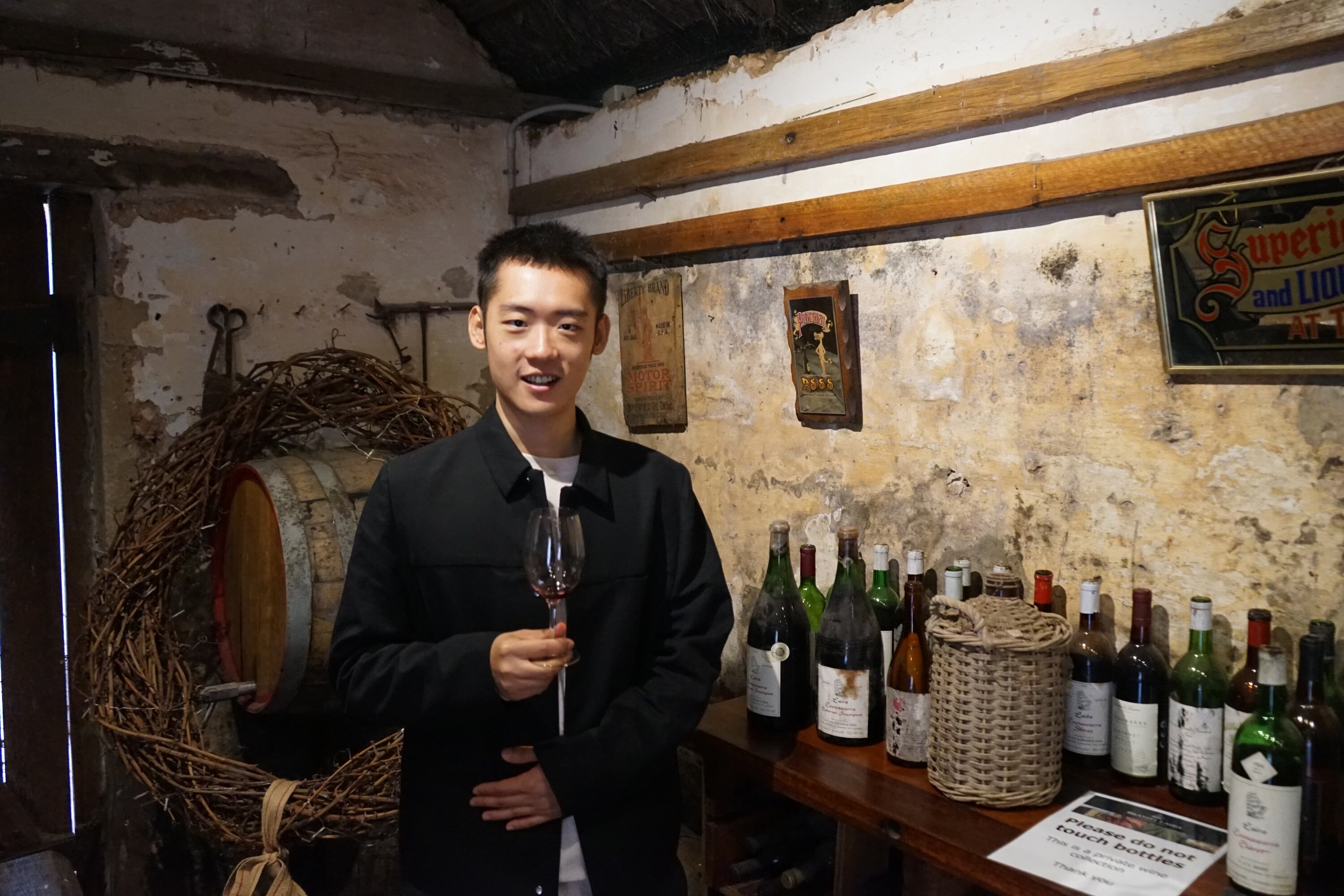A man holds a wine glass at a winery.