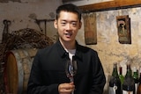 A man holds a wine glass at a winery.